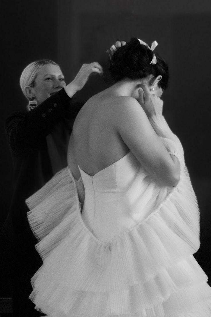 woman helping bride with her wedding attire
