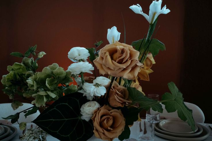 floral arrangement with brown flowers, white flowers, and green plants
