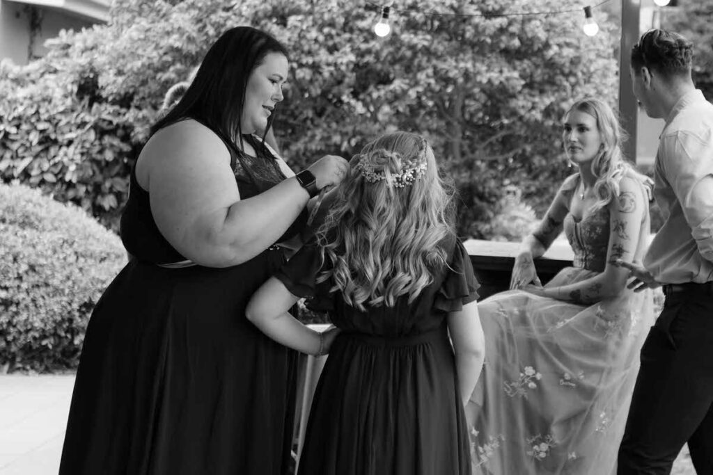 A person helping a small child do their hair at a wedding