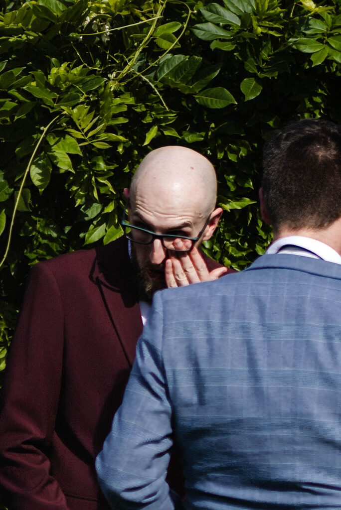 A groom wiping a tear away during a wedding ceremony