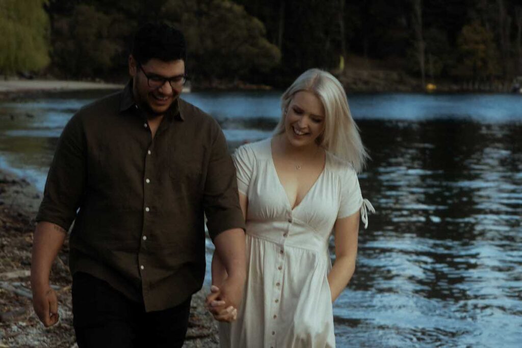 A couple smiling and holding hands on a walk