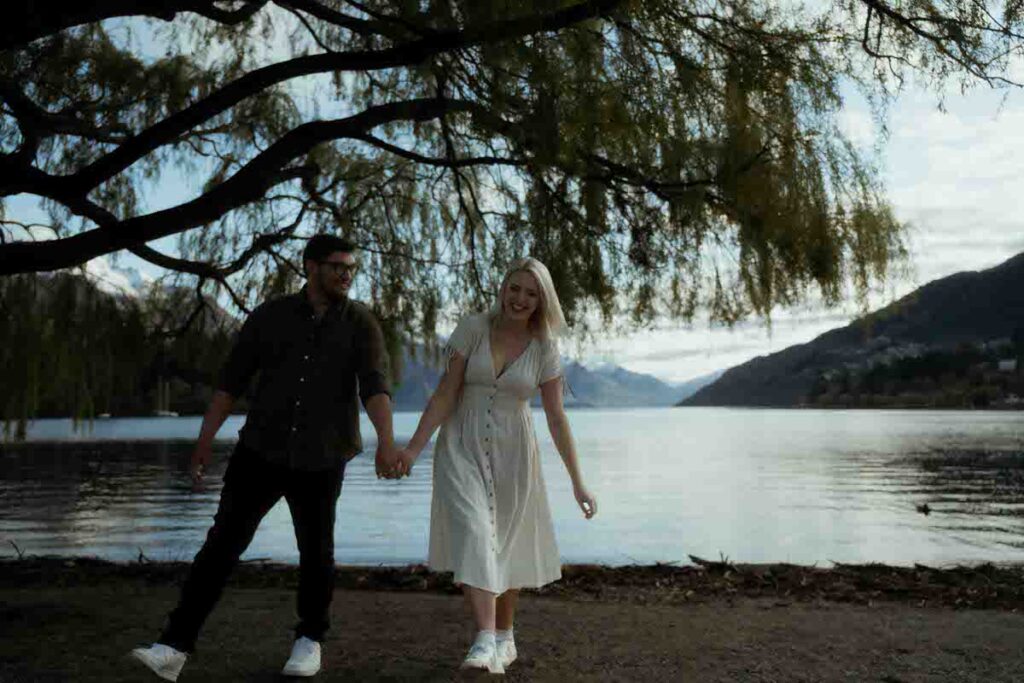A couple holding hands and walking together by a lake
