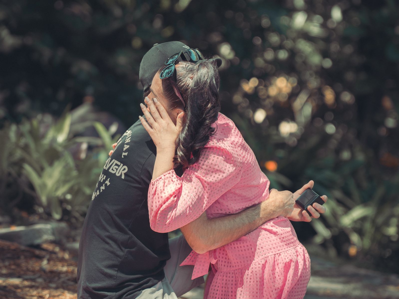 A woman hugging her partner and wiping tears from her eyes after her partner secretly proposed to her at Wendy's Secret Garden