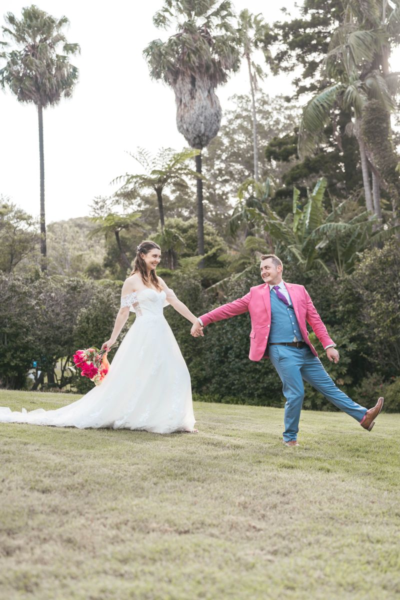 Bride and groom walking playfully across the lawn holding hands at Vaucluse House Sydney—documentary wedding photographer capturing joyful moments in heritage estate gardens