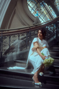 Bride in elegant white wedding dress seated on the ornate staircase inside the Queen Victoria Building Sydney with natural light from the dome ceiling—Japanese fine art wedding photographer capturing cinematic bridal portraits at iconic Sydney venues